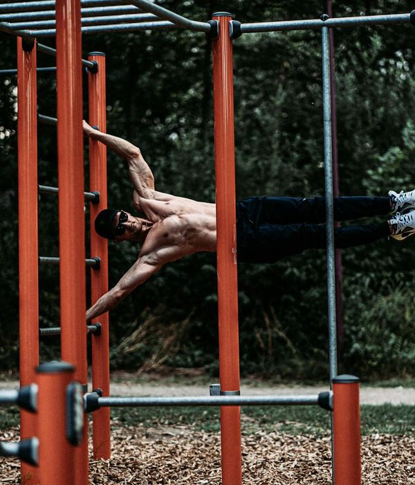 Man performing a controlled strength exercise in a minimalist dark gym.